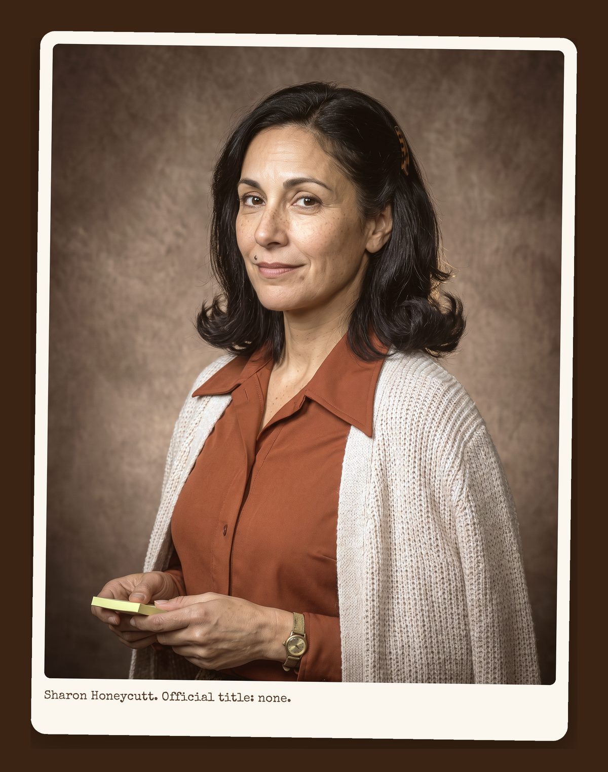 Sharon Honeycutt, dark hair, rust blouse and cream cardigan, holding a stack of sticky notes, directory portrait.